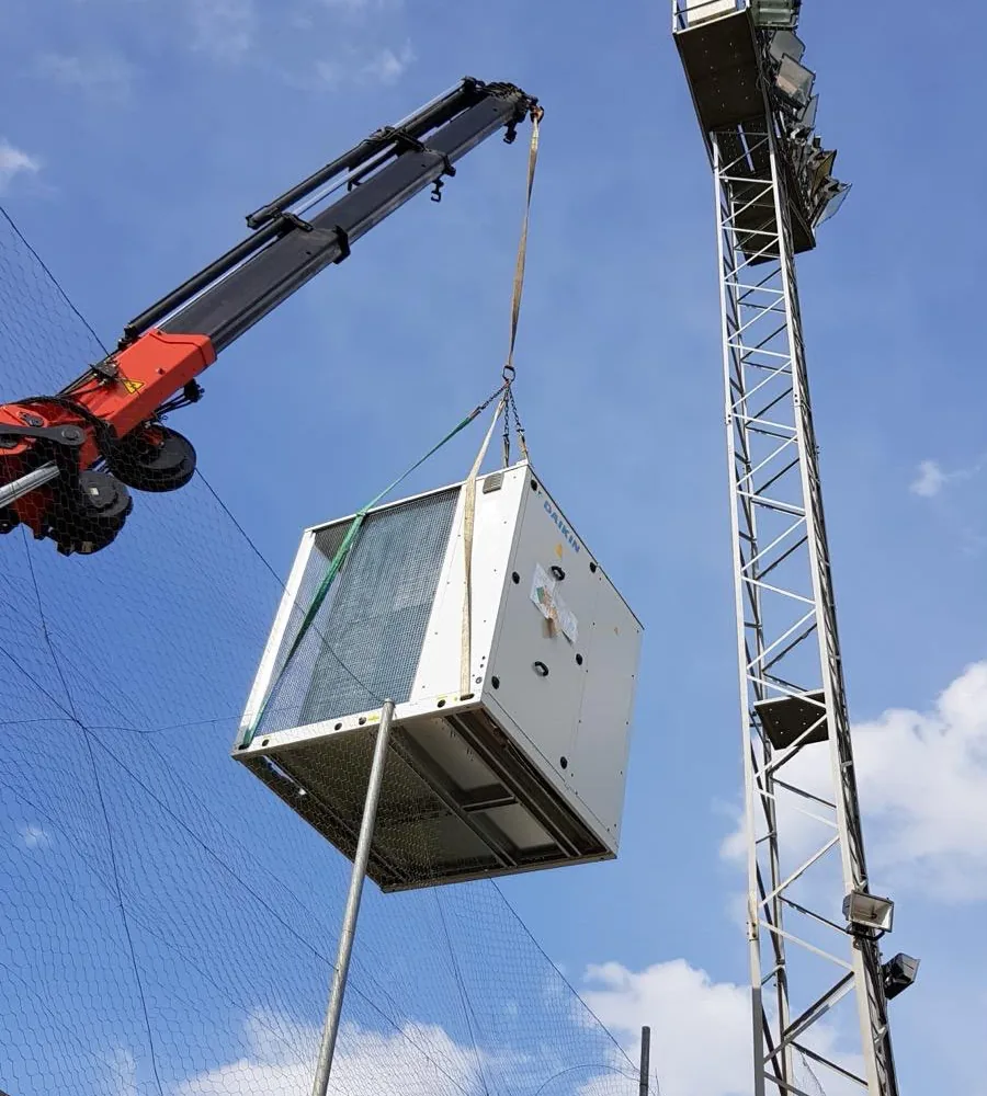 Máquina colgada de una grúa contra el cielo